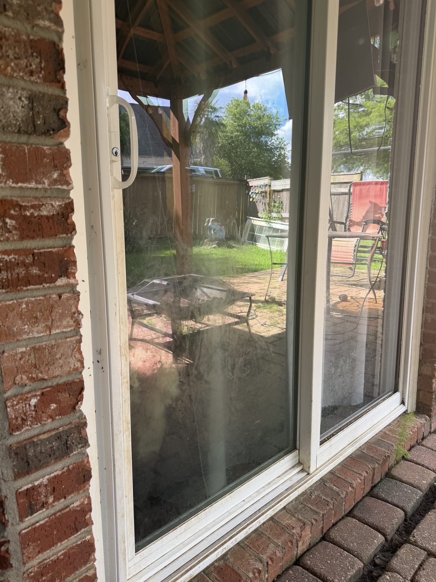 A sliding glass patio door with hazy, water-spotted exterior glass before cleaning